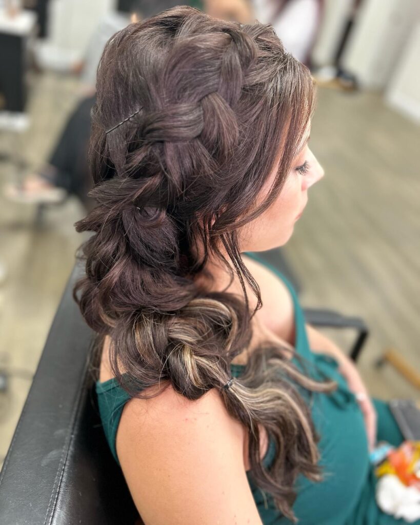 A side bubble braid with loose curls and soft highlights on medium brown hair.