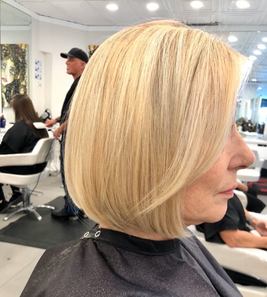 A side profile of a woman with straight hair wearing a classic buttery blonde chin length bob.