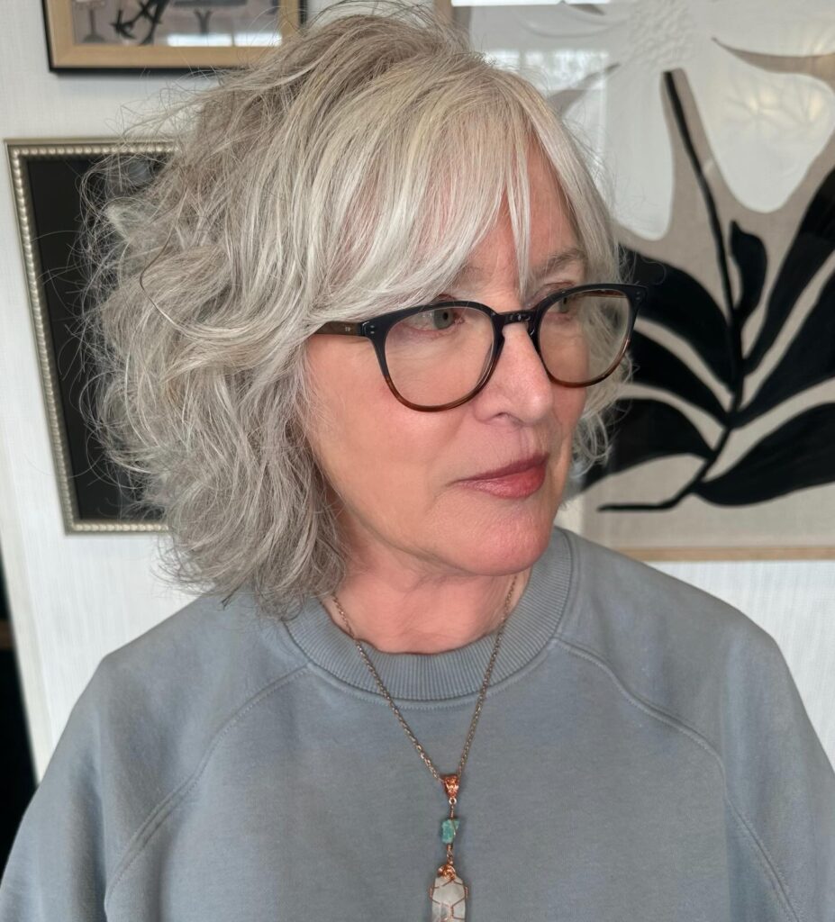 Silver shaggy bob with wispy bangs and soft layered waves framing the face.