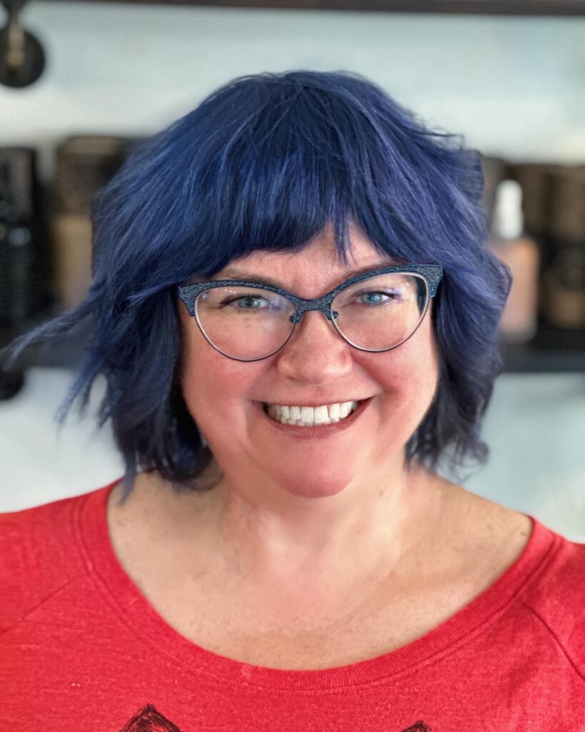 Midnight blue shaggy bob with textured waves and full fringe bangs.