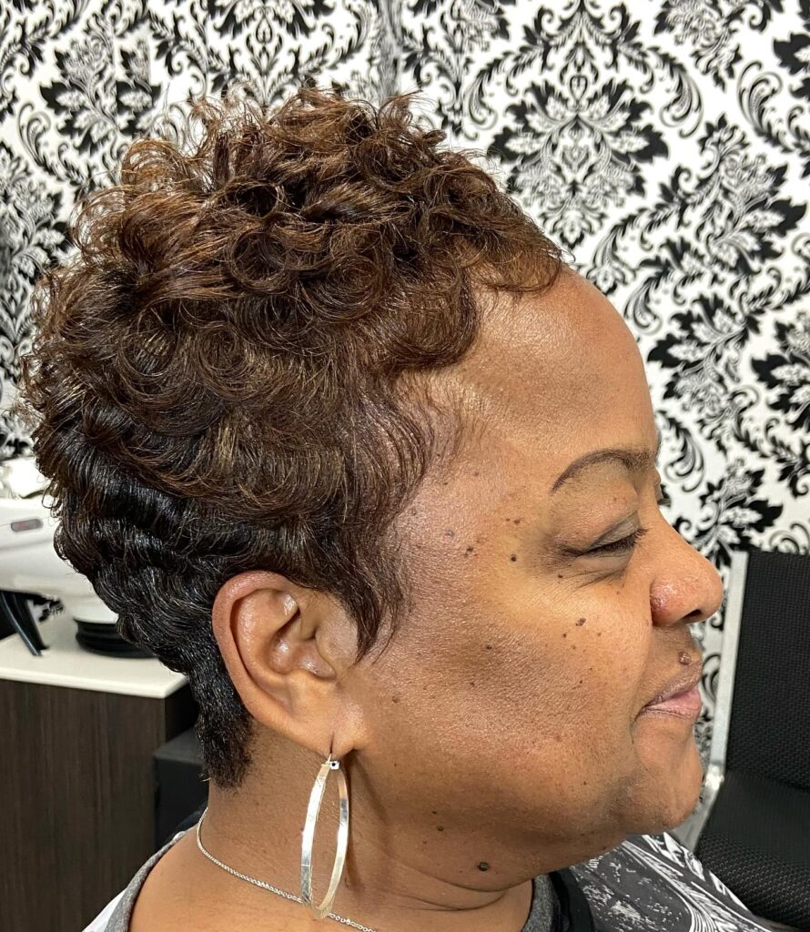 A woman with a short chestnut brown pixie cut featuring glossy sculpted waves and tapered sides.