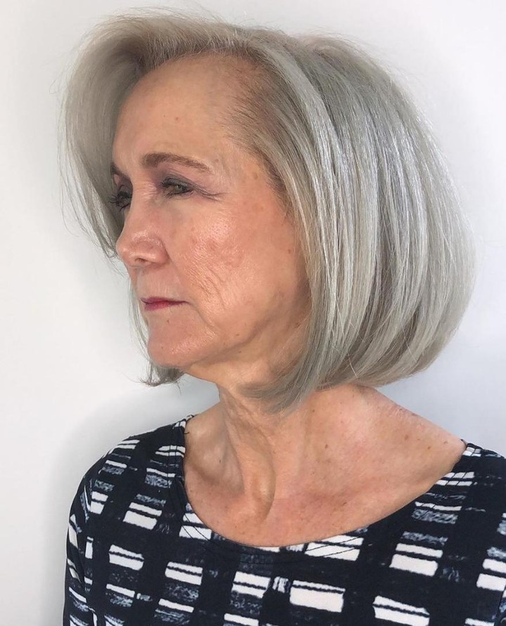 A woman over 60 with a sleek chin-length silver bob hairstyle featuring rounded ends and a side part.