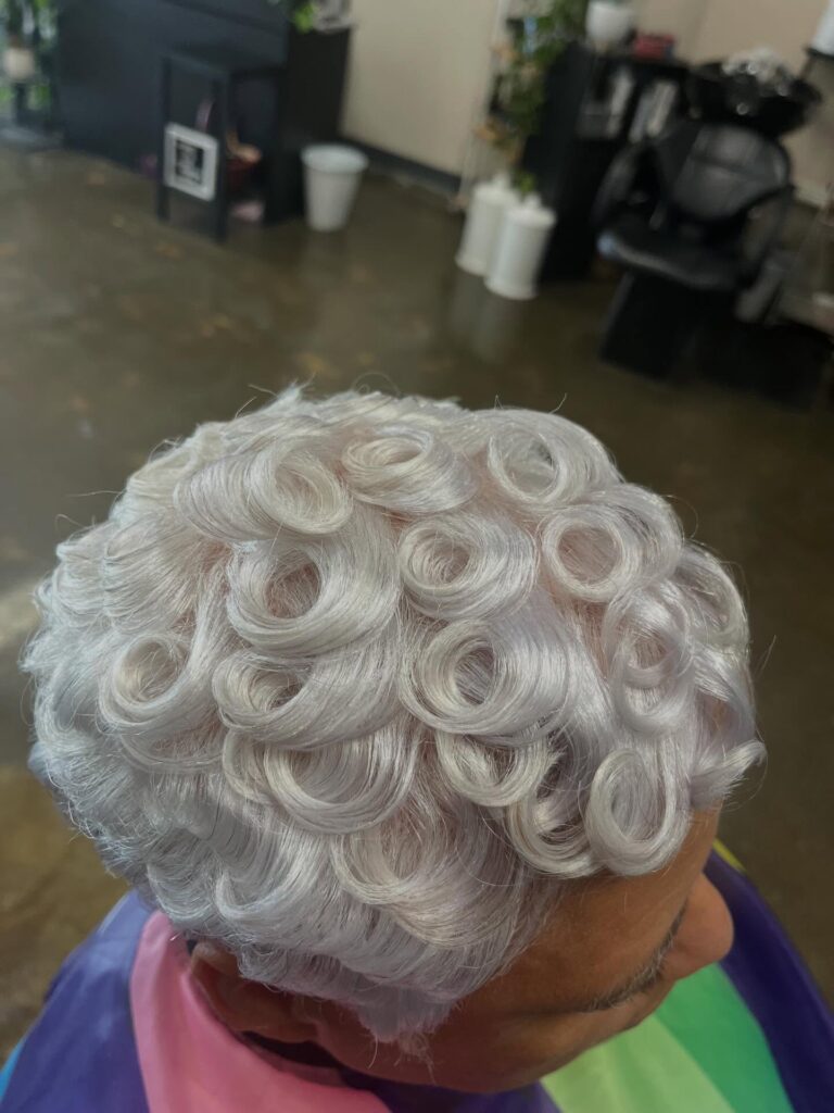 An overhead view of a woman with short silver hair styled into precisely sculpted pin curls across the entire head.