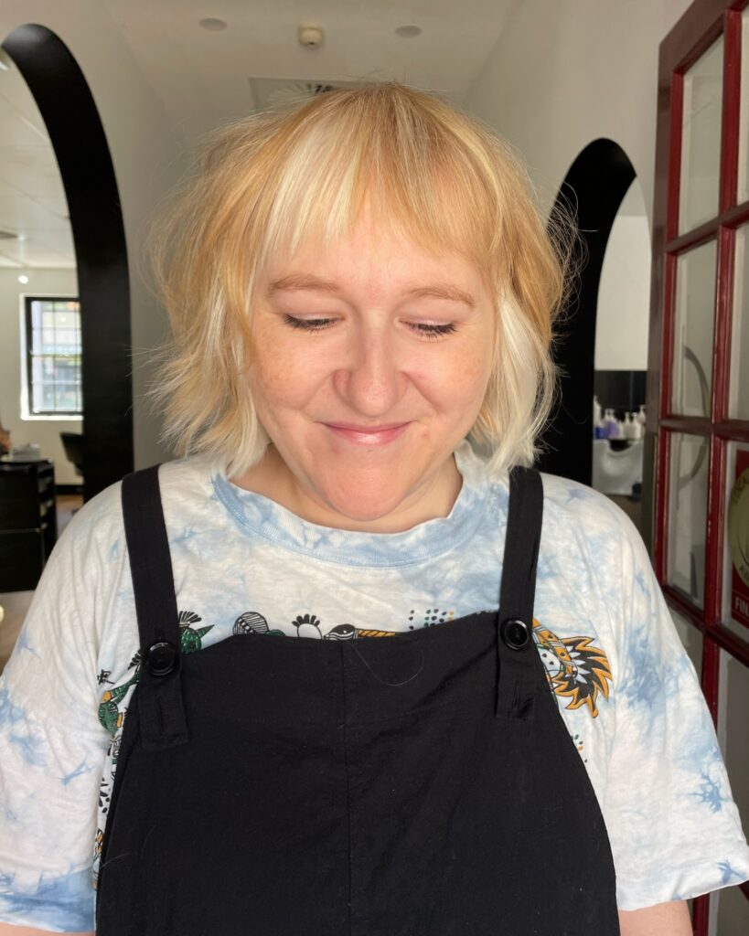 Blonde shag bob with wispy bangs and choppy textured layers.