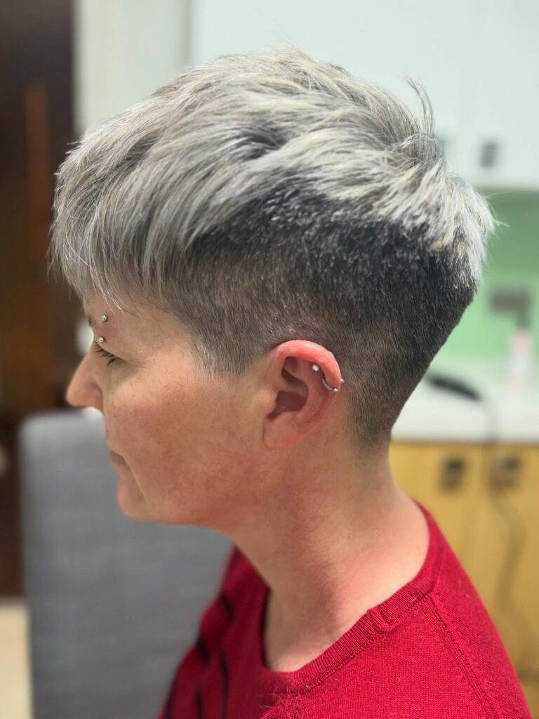 Silver textured pixie haircut with an undercut and longer swept layers on top.