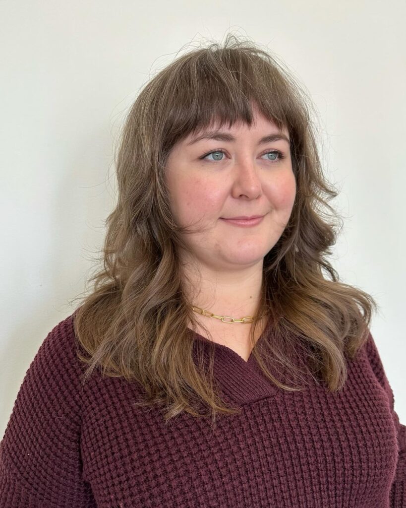 Medium layered wolf cut with wispy bangs and soft brunette waves.