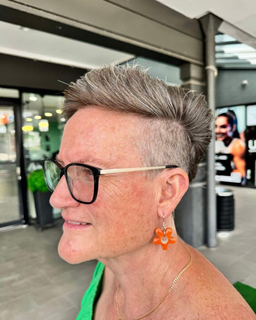 Salt-and-pepper undercut pixie with swept-back volume on top.