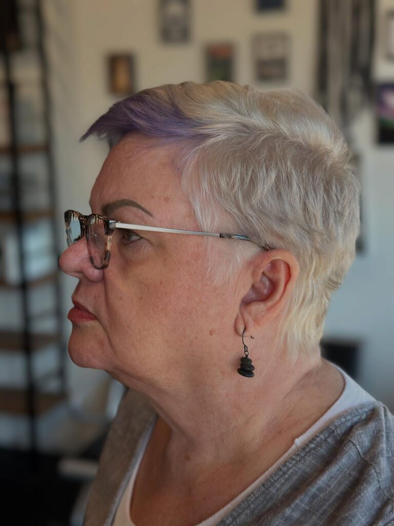 Short silver crop haircut with textured layers and a lavender front accent.