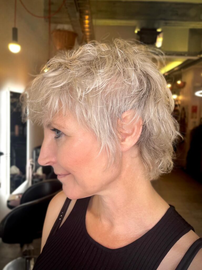 Silver shag pixie haircut with tousled layers and wispy bangs.
