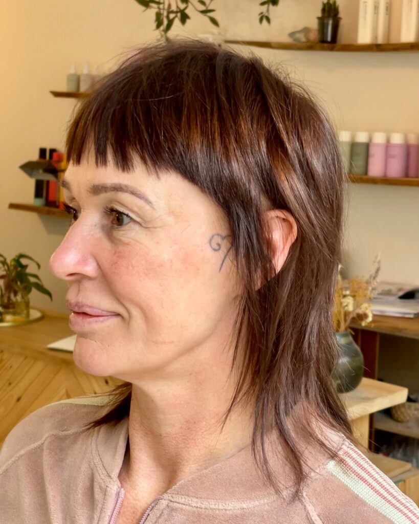Brunette shag haircut with micro bangs and layered textured ends.