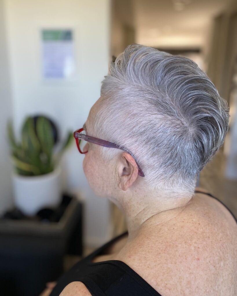 Silver undercut hairstyle with shaved sides and slicked back volume on top.