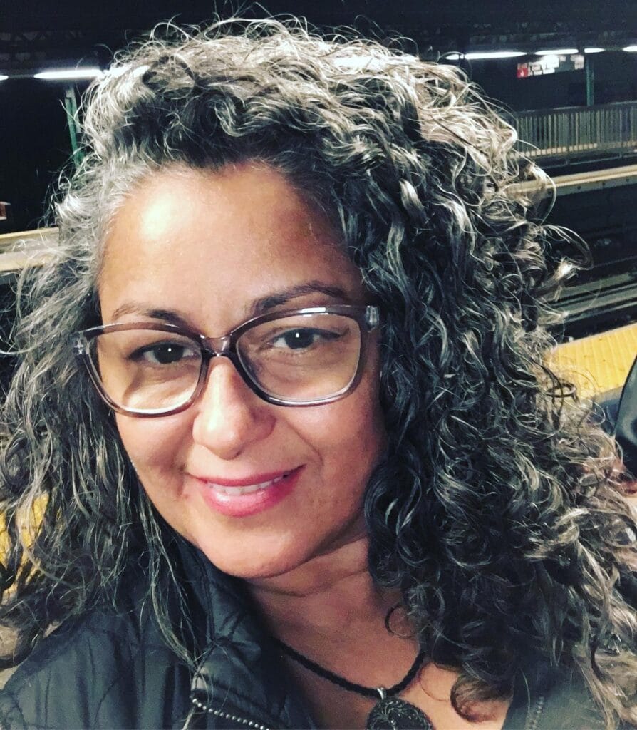 Shoulder length dark curly hairstyle with defined spirals and subtle gray strands.