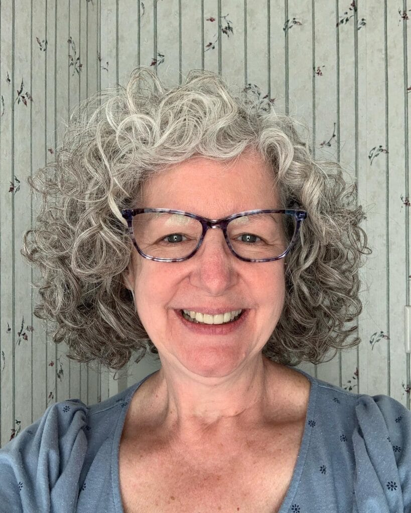 Short rounded silver curly bob with soft layers and natural volume.