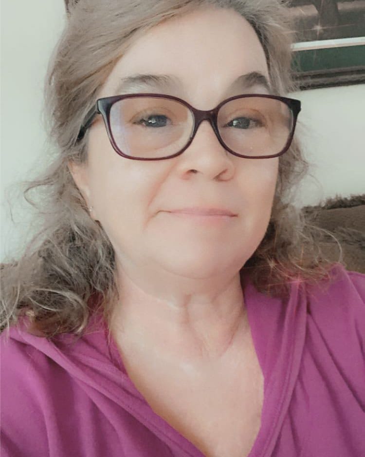 Shoulder length gray curly hairstyle with soft layers and curls framing the face with glasses.