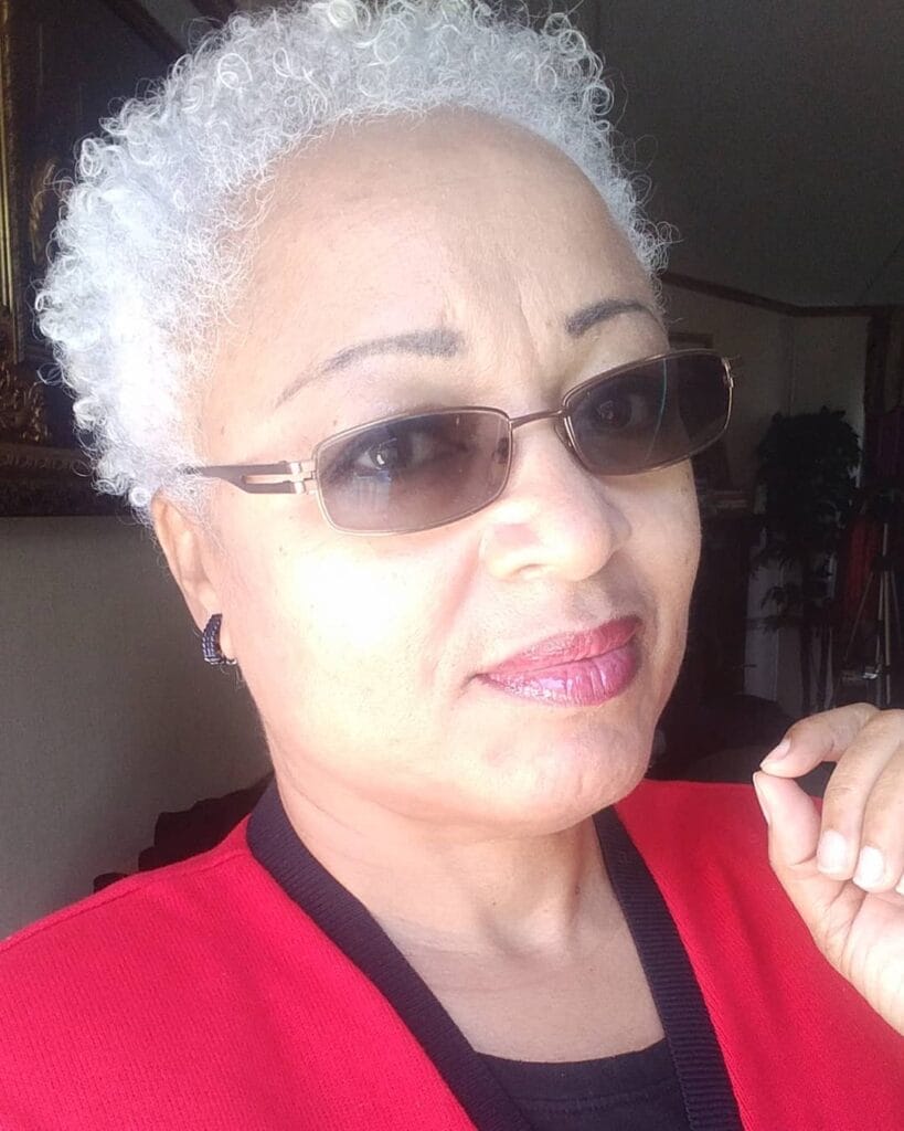 Short silver curly cropped hairstyle with tight curls and soft rounded shape.