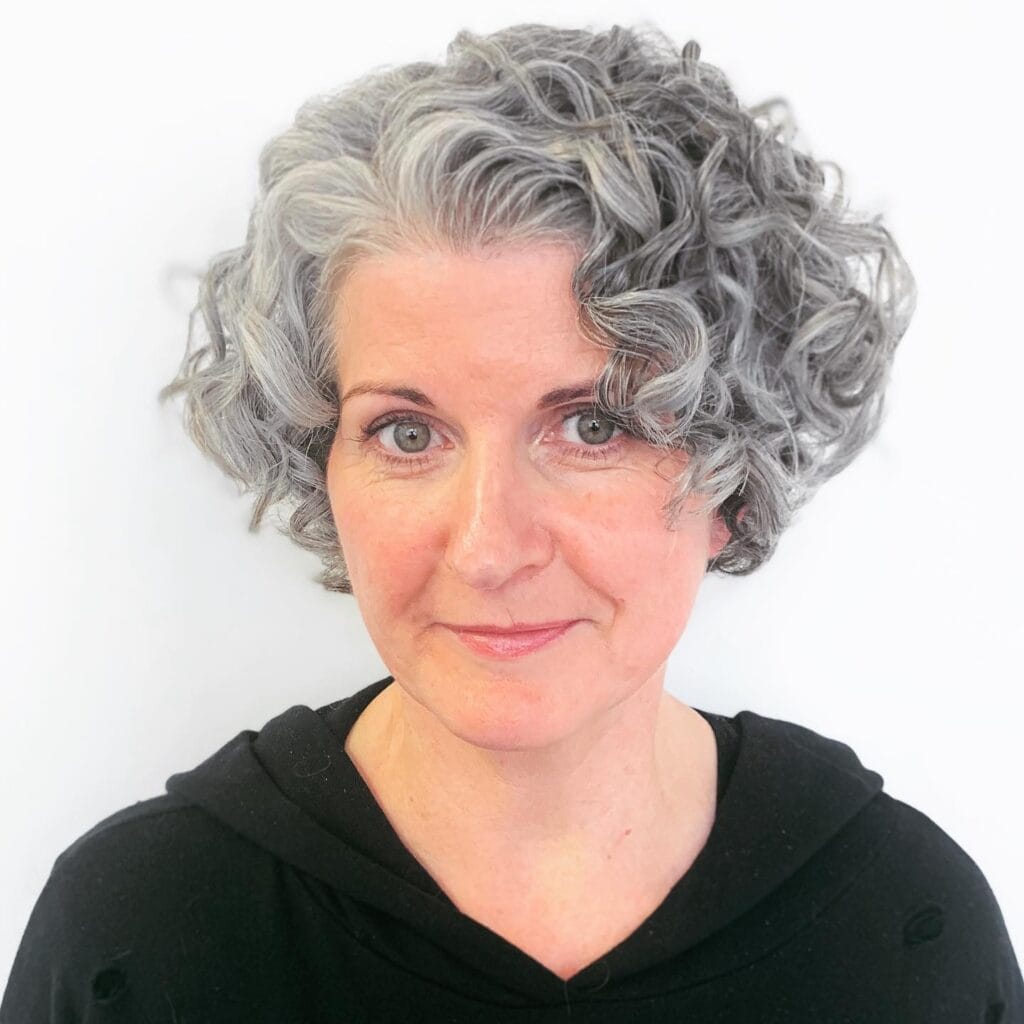 Short gray curly bob with soft sculpted curls framing the face.
