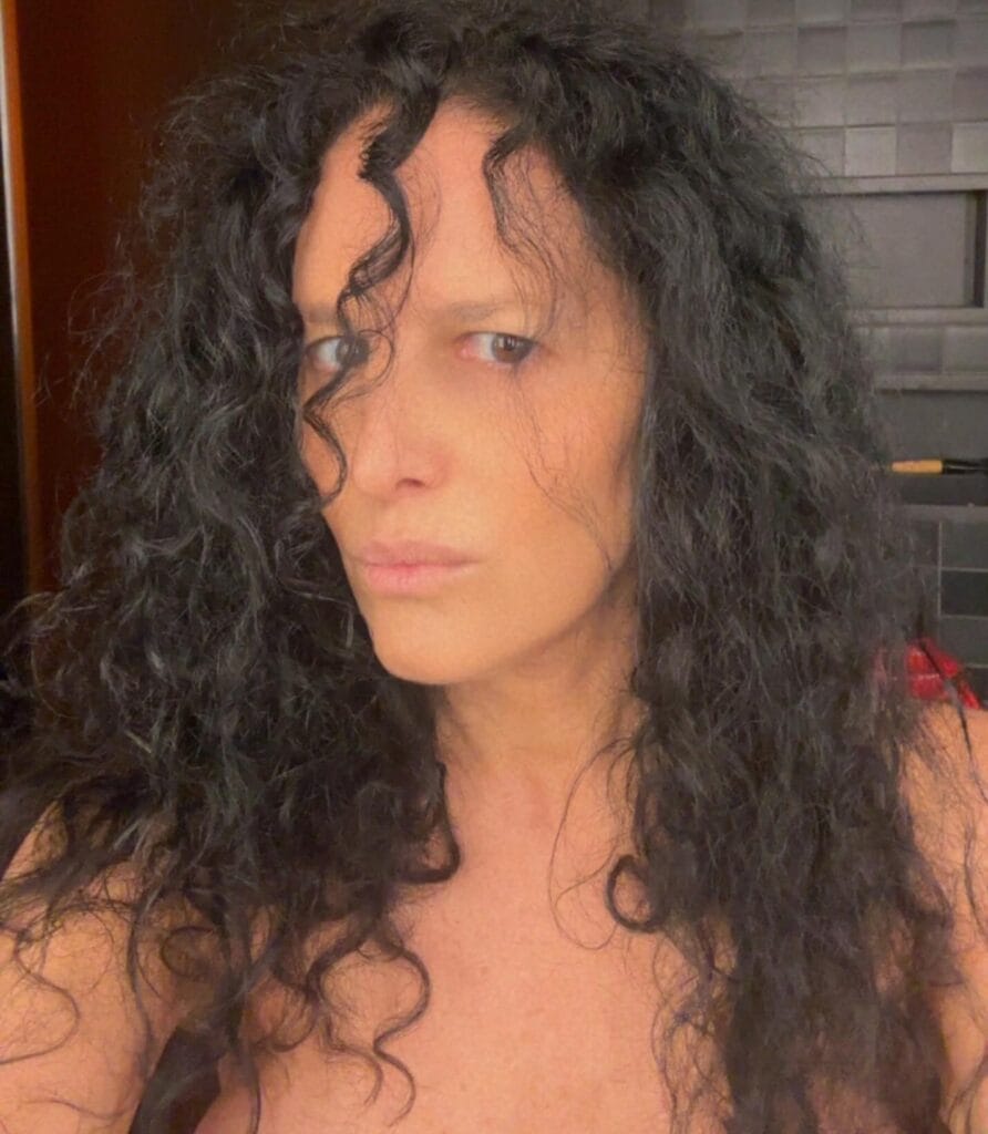 Long dark natural curly hairstyle with loose textured curls past the shoulders.