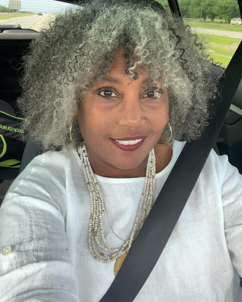 Full rounded hairstyle with natural gray curls and lots of soft volume.