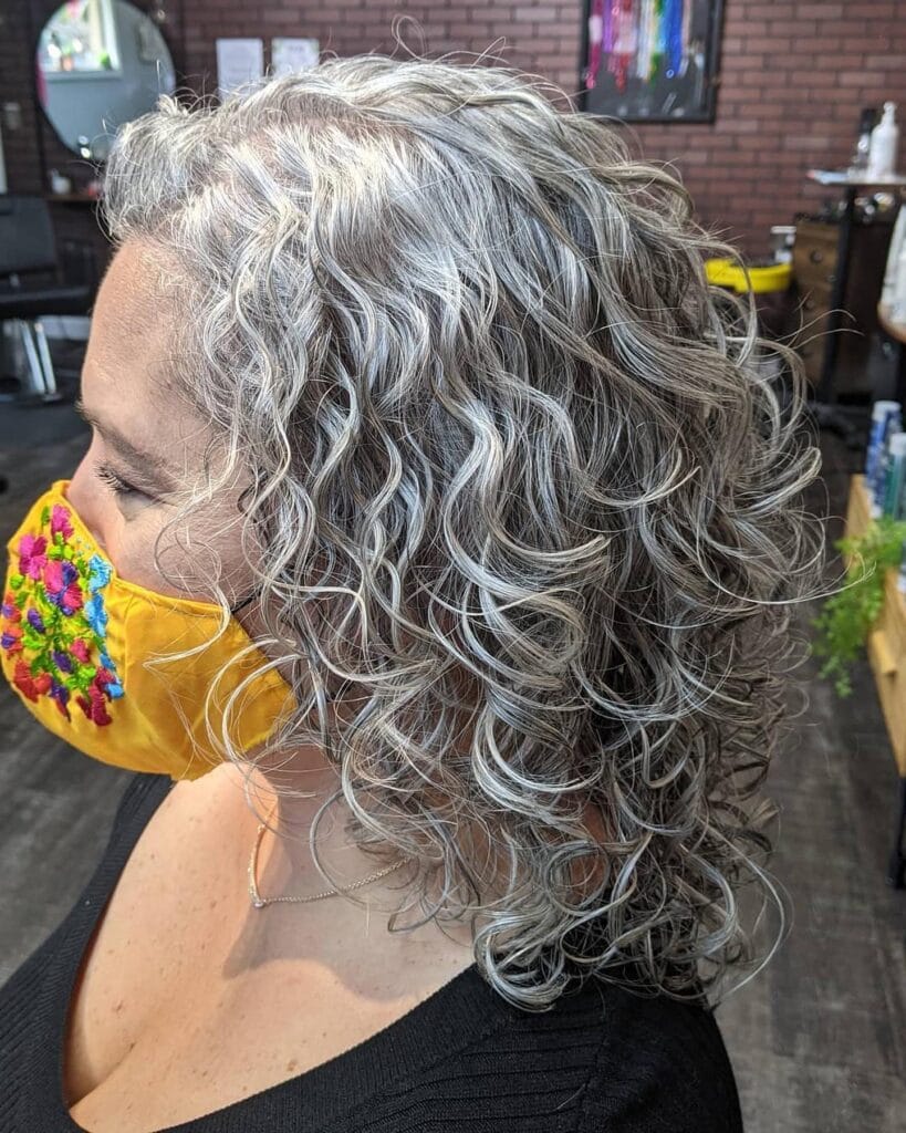 Shoulder length silver curly hairstyle with soft layers and natural movement.
