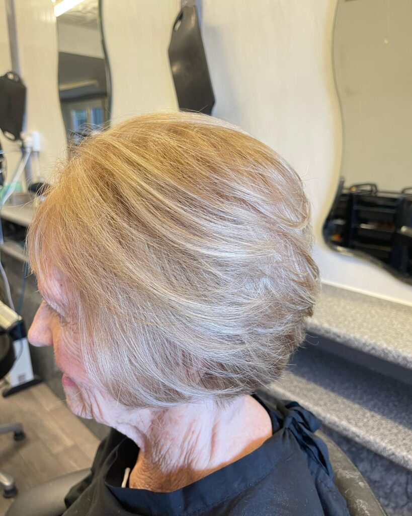 A woman from a side profile view displays a textured chin-length dark brunette shaggy bob with wispy bangs and soft waves.