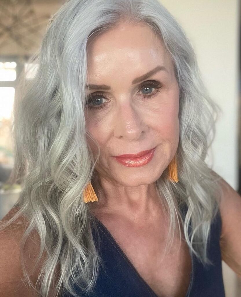 A woman over 60 with wavy, shoulder length silver hair looking forward at the camera.