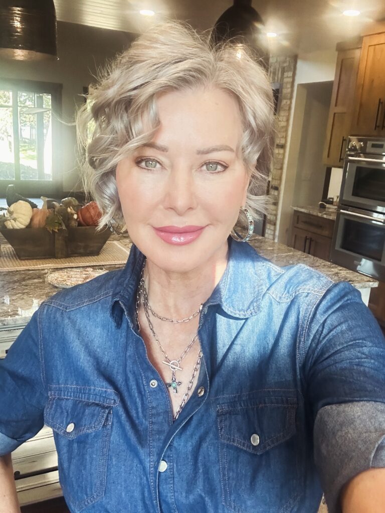 A stylish woman over 60 with a jaw-length ash-blonde bob haircut styled in elegant, voluminous waves.