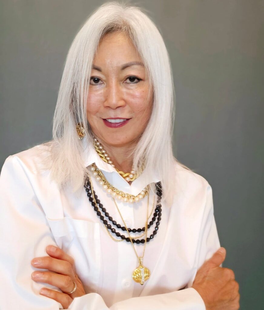 A woman over 60 with a straight, collarbone-length white-silver lob hairstyle and a center part.