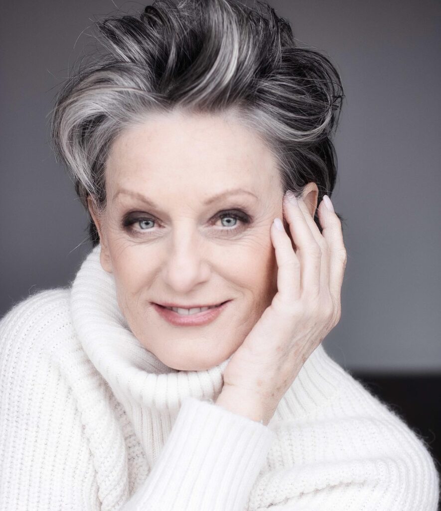 A woman over 60 with a short, spiky salt-and-pepper pixie cut styled with volume at the crown.