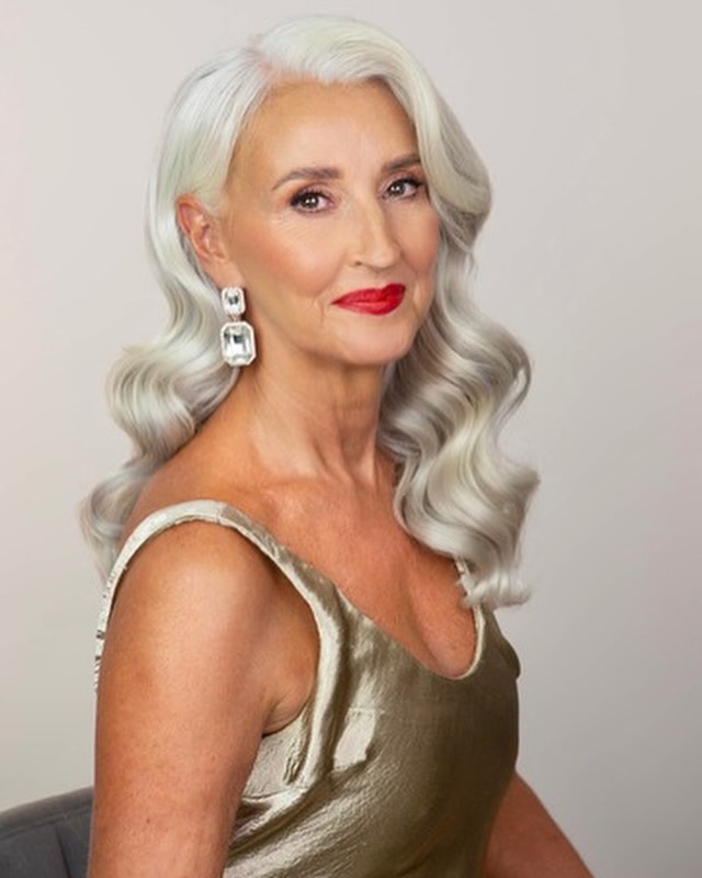 A woman with bright red lipstick and square crystal earrings models her long, perfectly sculpted vintage Hollywood silver waves.