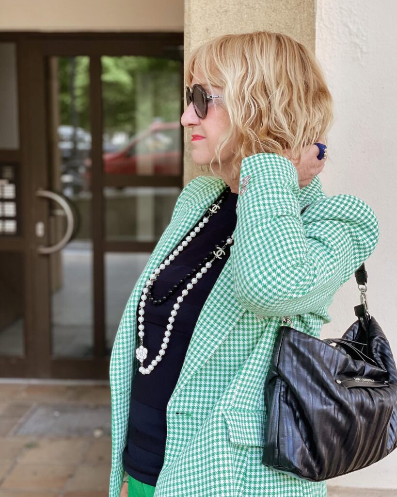 A woman viewed from the side showcasing a wavy chin-length golden blonde bob with a green houndstooth blazer.