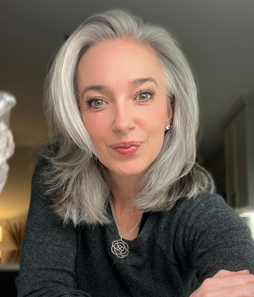 A woman with a bouncy silver and gray layered lob haircut styled with a deep side part.