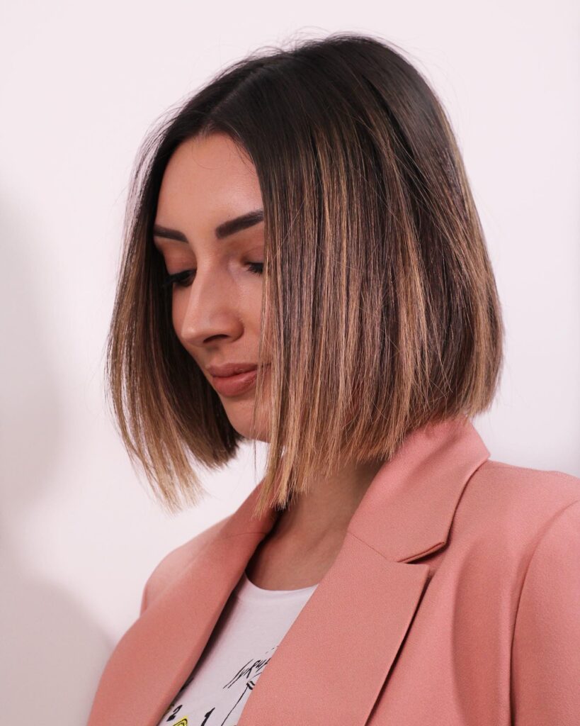 Straight blunt bob with soft beige balayage and a center part.