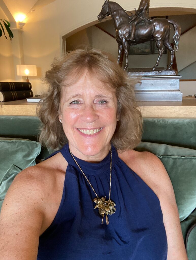A smiling woman with a golden honey-blonde bob and soft wispy curtain bangs.
