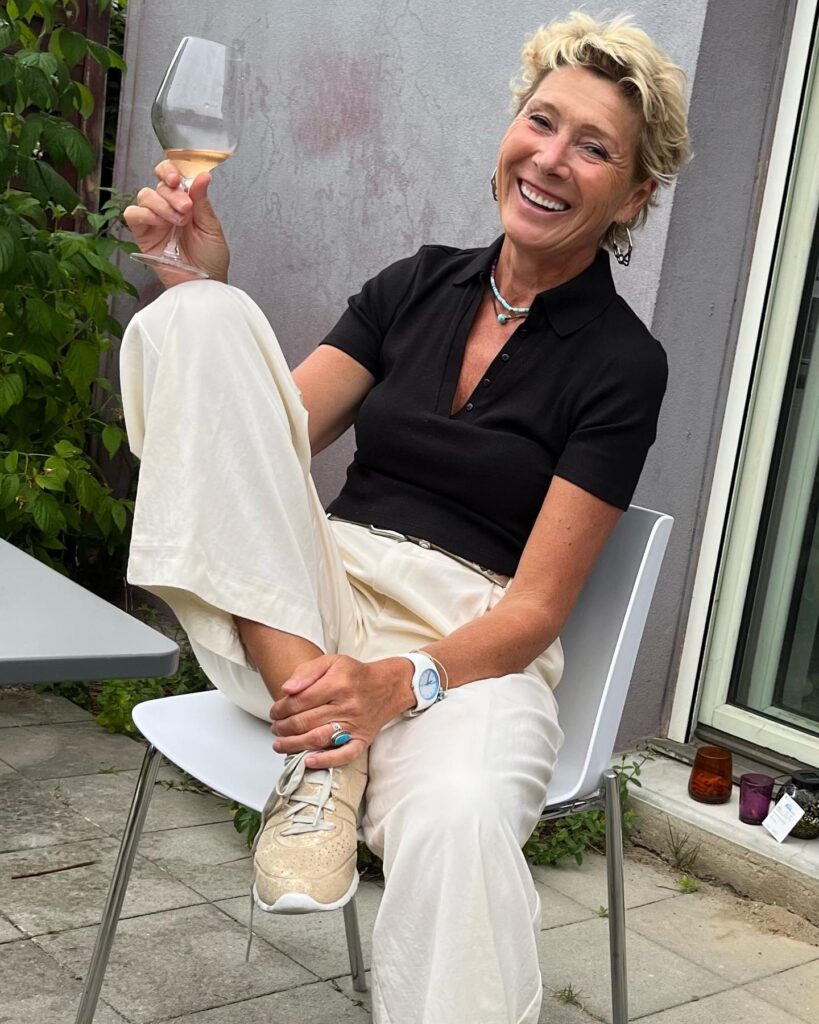 A woman with a short, textured sandy blonde pixie cut featuring a side sweep and no bangs.