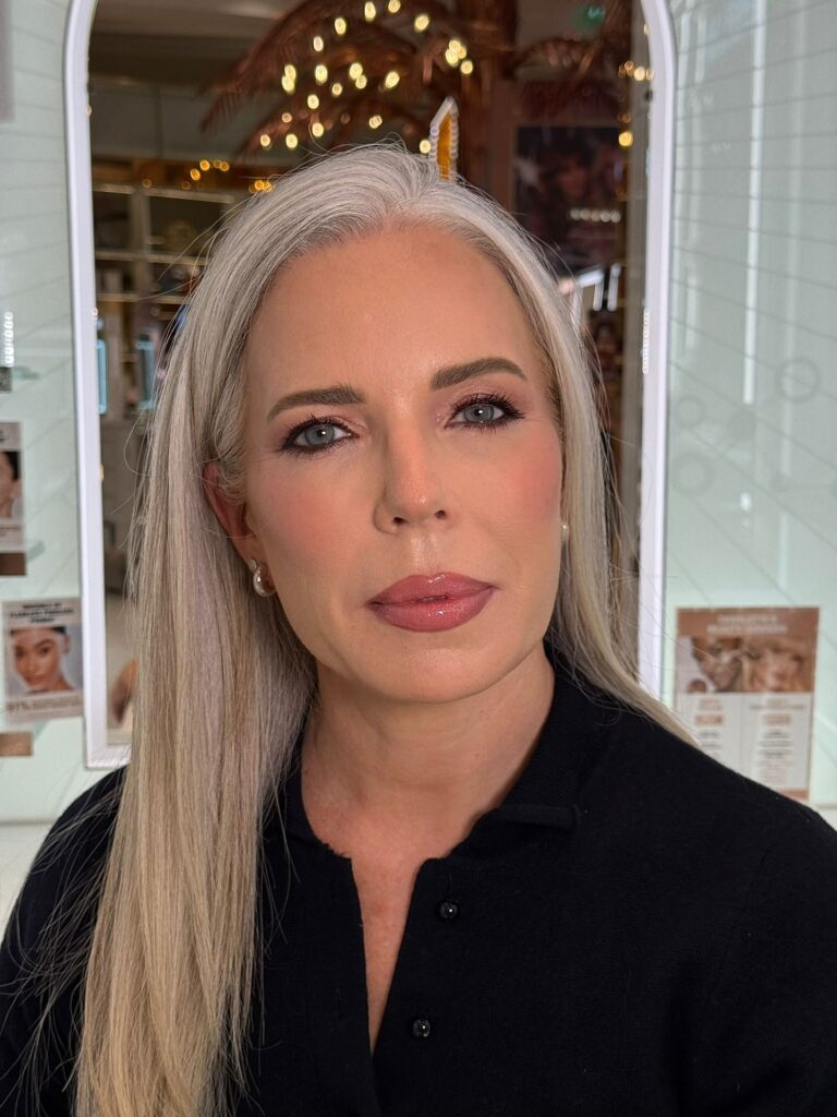 A woman over 60 with long, pin-straight silver hair styled with a side part and no bangs.
