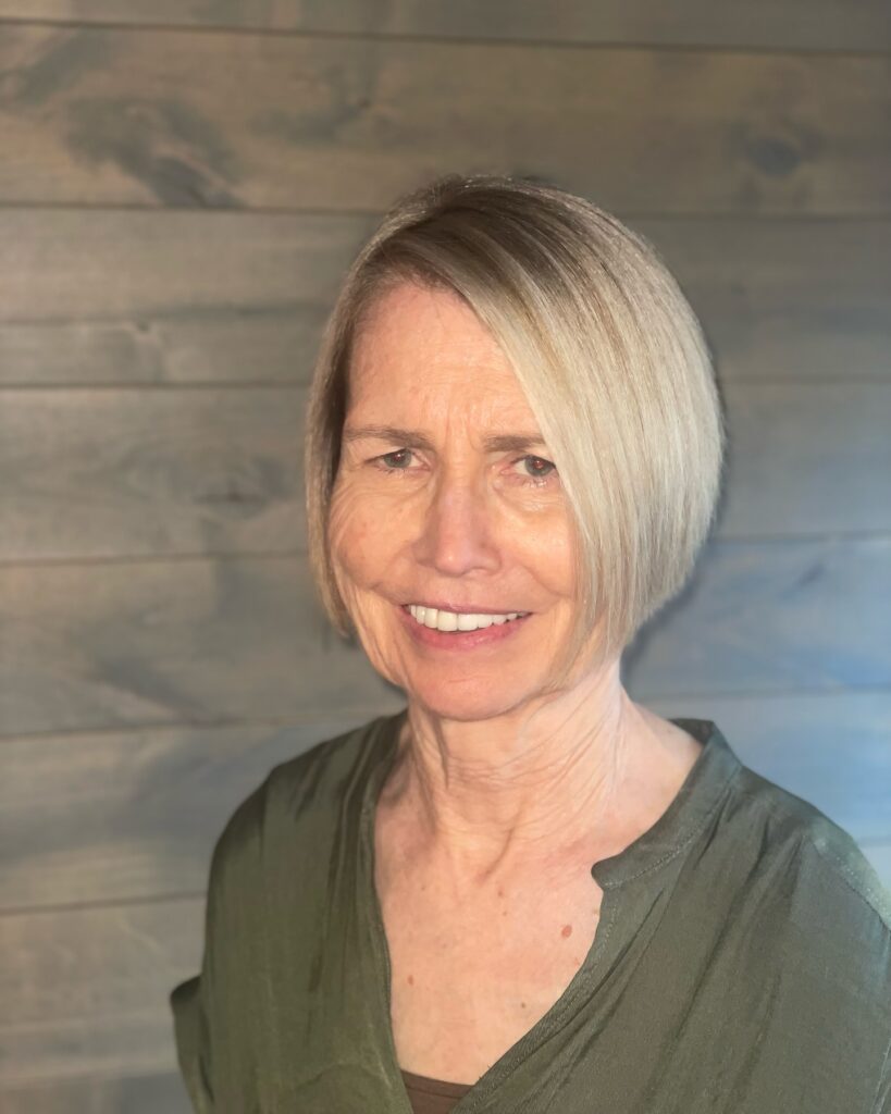 A woman over 60 with an airy, layered champagne blonde bob cut to the chin without bangs.