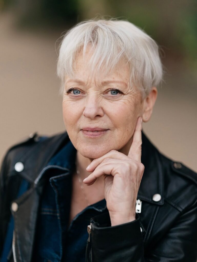A woman with a short platinum-white pixie cut and soft wispy bangs that rest high on the forehead.
