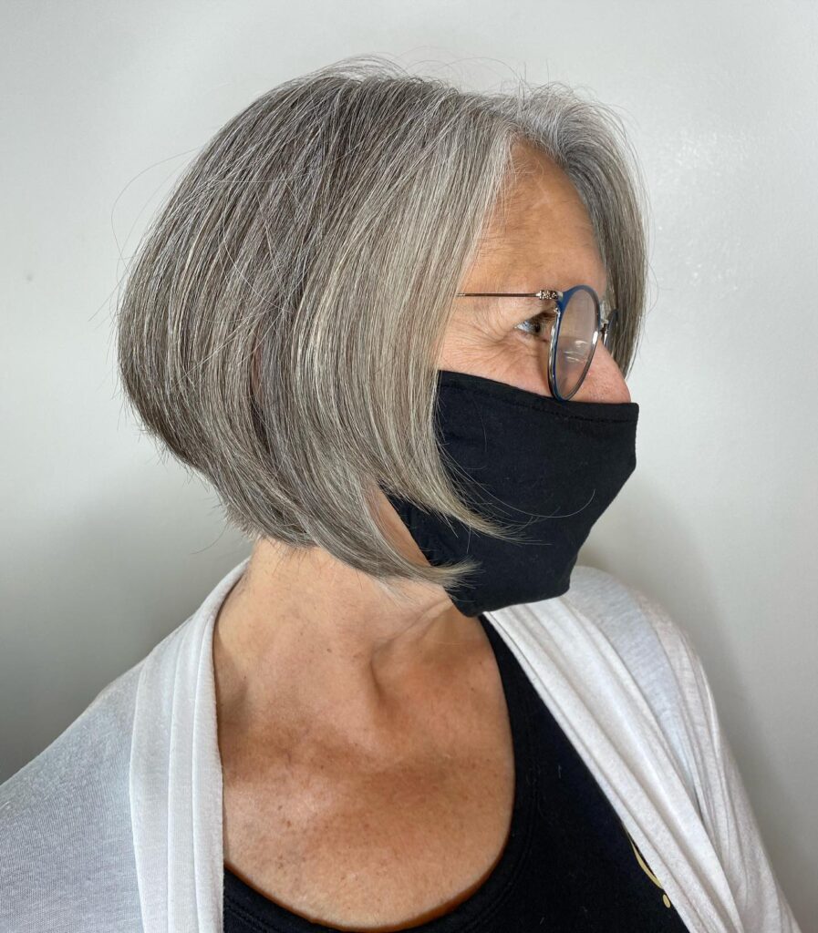 A woman with a sleek silver and gray inverted bob hairstyle featuring tapered back and angled front layers.