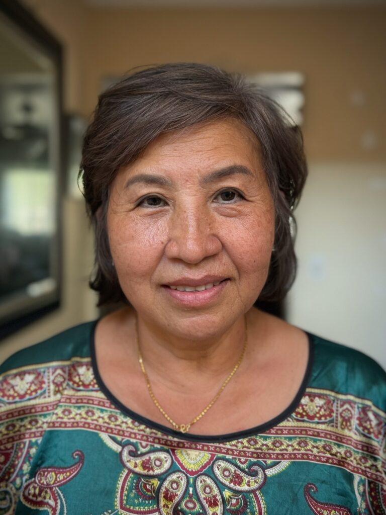 A front view of a woman with a side-swept ash-brown bob that reaches just above the shoulders.