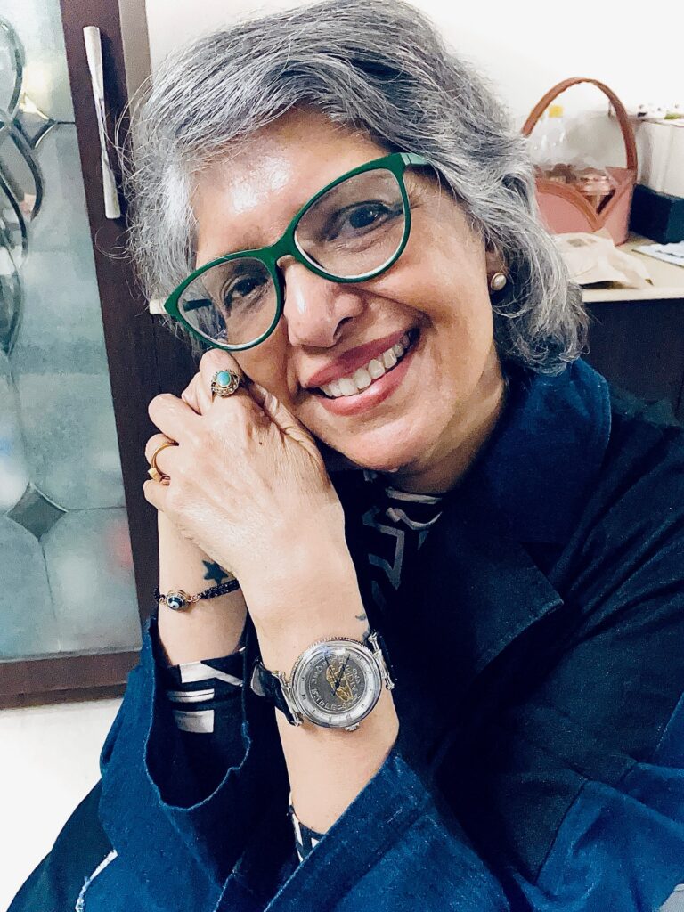 A smiling woman over 60 with a round face wearing a textured salt-and-pepper bob with a side-swept front.