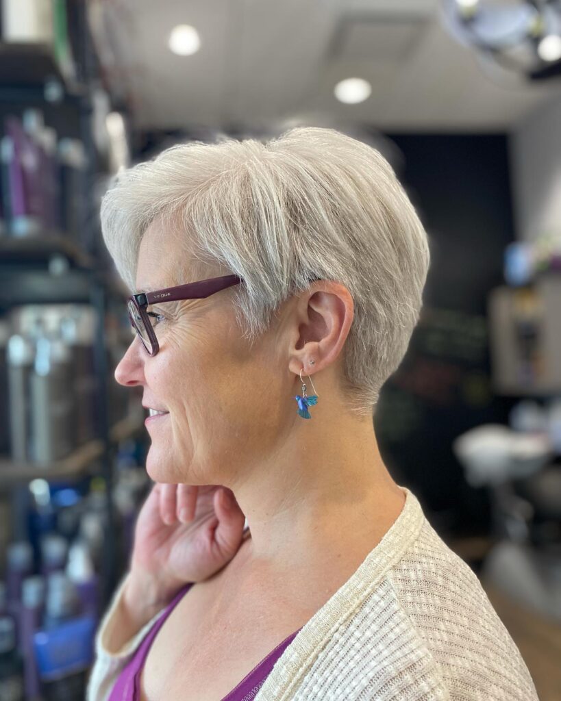 A woman in profile wearing a polished pearl white pixie cut with tapered sides and smooth top layers.
