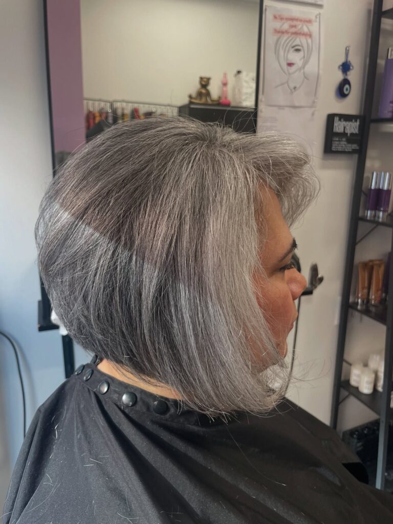 A woman with an elegant pewter-grey inverted bob hairstyle with longer front pieces and a shorter back view.
