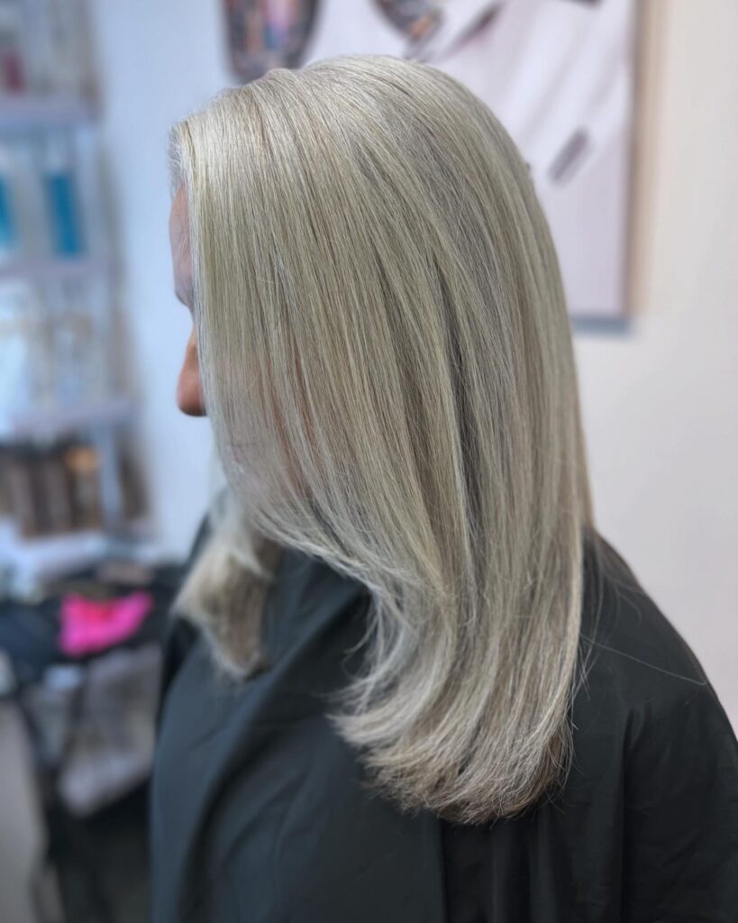 A woman with a sleek, medium-length platinum blonde layered bob that curves gently at the ends.