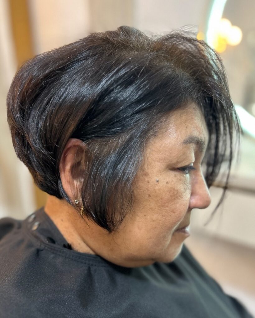 A woman is shown in profile with a dark espresso short bob featuring voluminous layers and a tapered back.