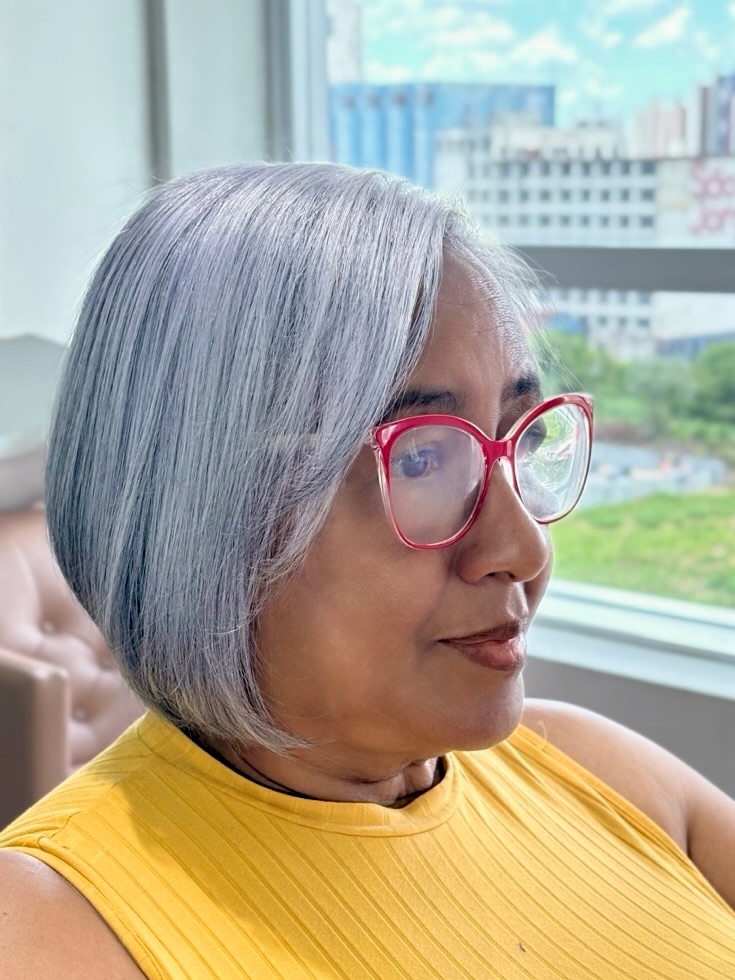 A woman over 60 with a straight-angled bob in a shimmering, icy lavender-and-silver shade.