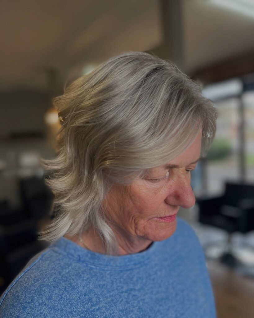 A woman over 60 with a silver layered bob featuring flicked-out ends and a side-swept fringe.