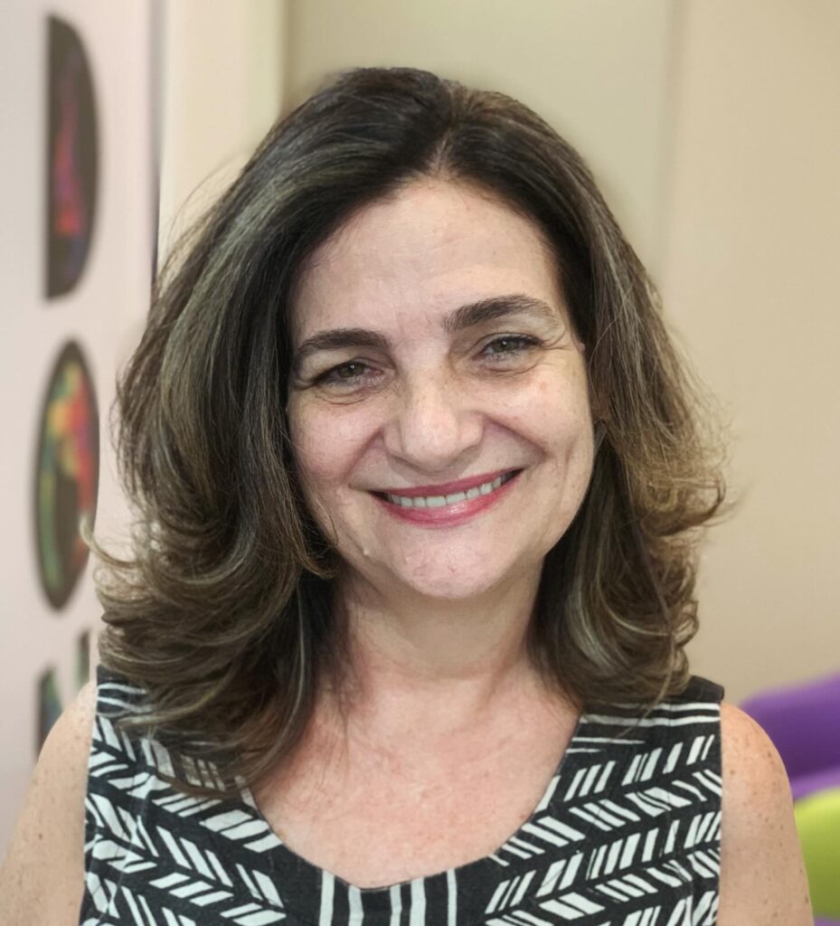 A smiling woman with a medium-length brunette bob featuring voluminous layers and flipped-out ends.