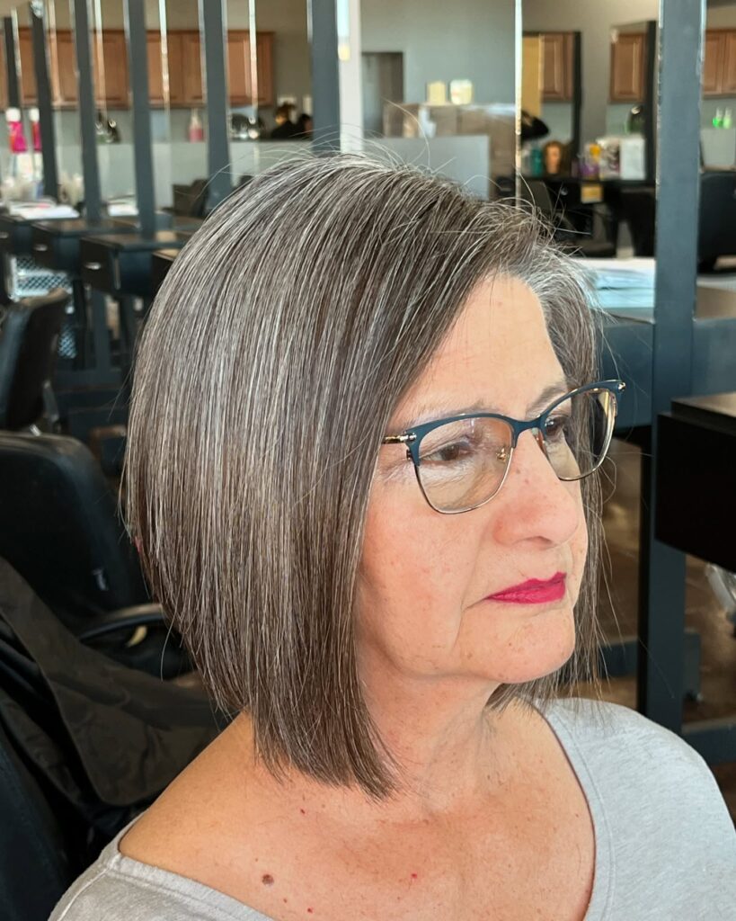 A woman over 60 with a straight, angled medium bob in a salt and pepper color.