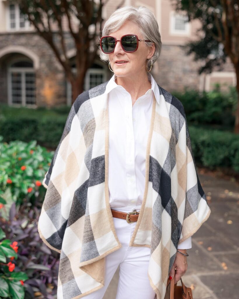 A stylish woman over 60 wearing red sunglasses and a sculpted silver pixie cut with a soft side sweep.