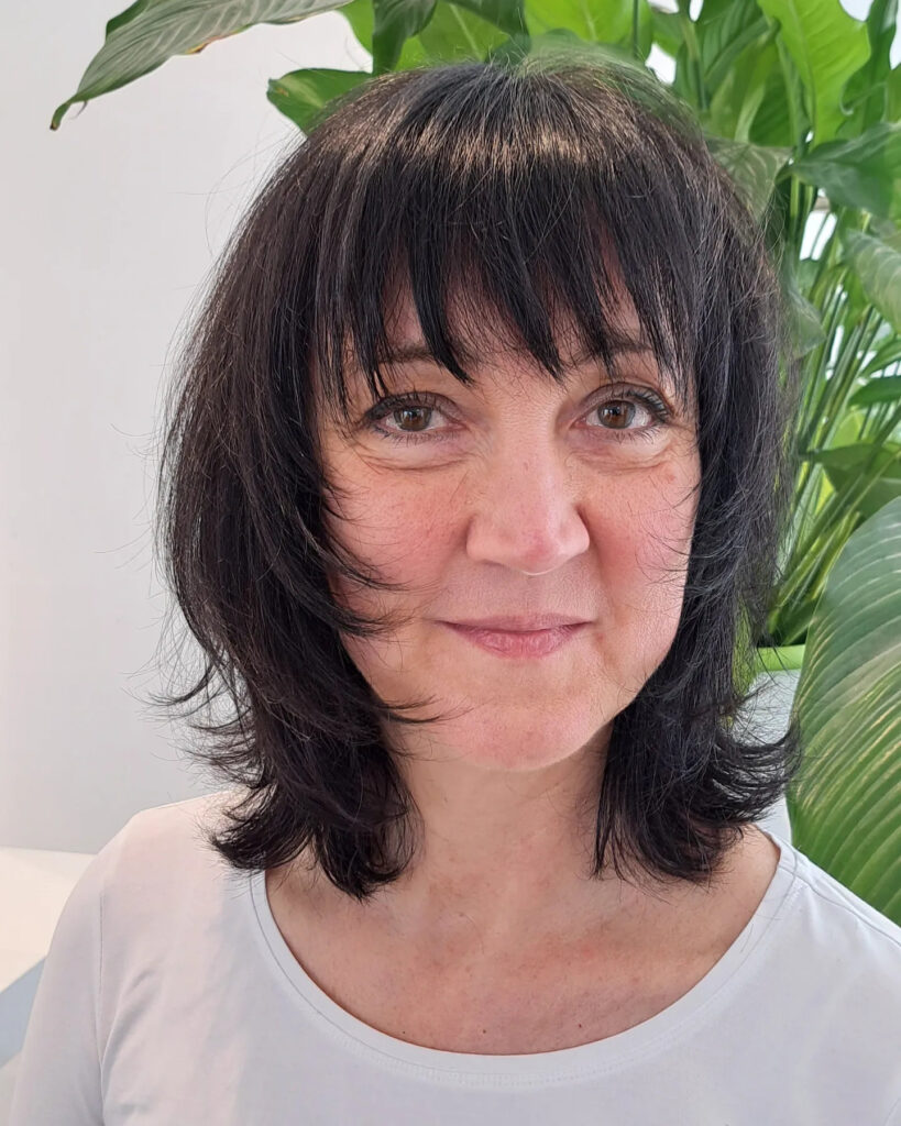A woman with a sleek black neck-length shag haircut featuring flicked-out ends and full bangs.
